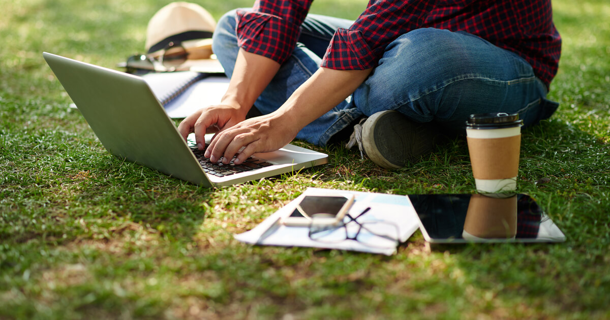 Ein Student, der auf dem Boden sitzt und an einem Laptop arbeitet